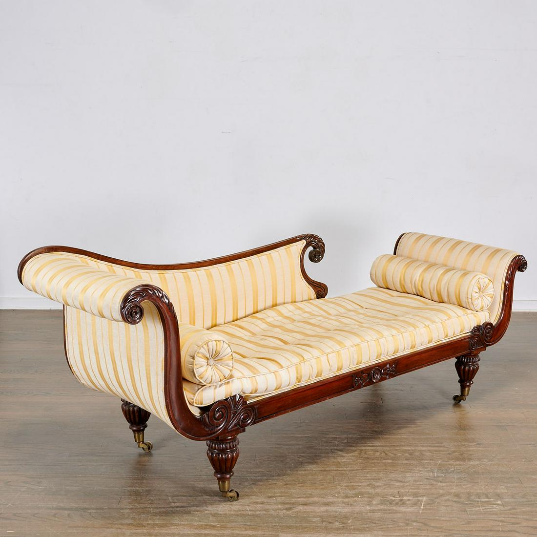 William IV carved mahogany recamier: William IV carved mahogany recamier, 19th c., the frame relief carved with rosettes and leaf fronds, with scroll arms and tapered baluster foot, striped silk upholstery, 32"h x 77"l x 22"w, 17"h (to s