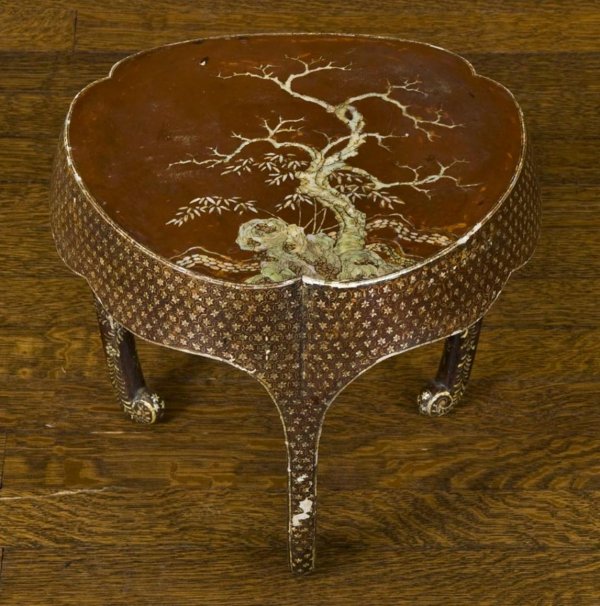 Antique Asian mother-of-pearl inlaid lacquer stand: Antique Asian mother-of-pearl inlaid lacquer stand, 19th Century, probably Japanese or Korean, the trefoil top with craggy tree and rock decoration on 3 incurving legs, 11"h x 12"dia. Provenance: The 