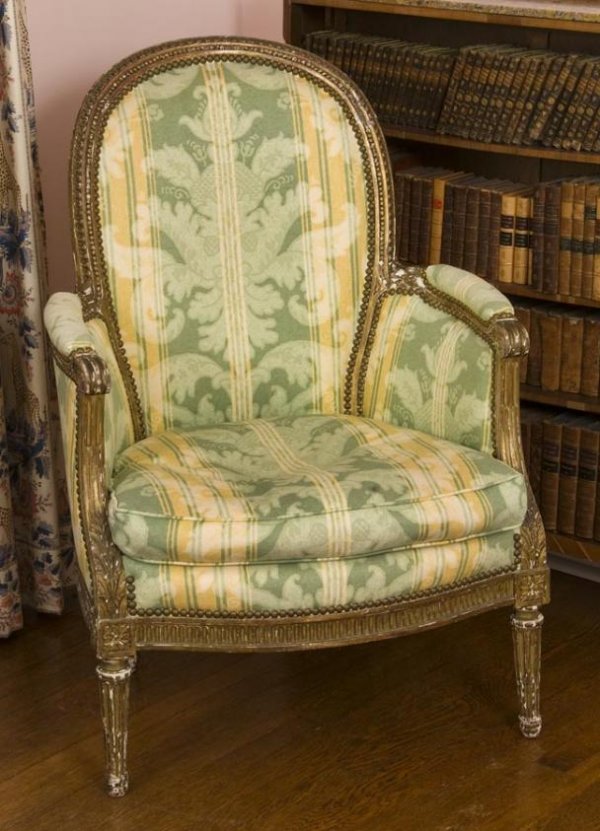 Antique Louis XVI style giltwood bergere: Antique Louis XVI style giltwood bergere, 19th Century, the bead and leaf-carved frame with close-nailed upholstery and loose cushion seat on round tapering fluted legs, 37.5"h x 26.5"w x 22"d Provena