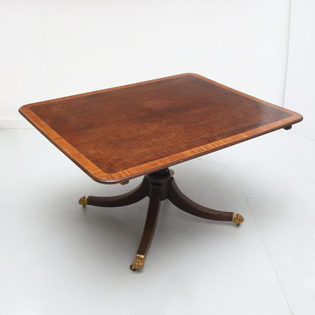 Antique George III style tilt top breakfast table: Antique George III style tilt top breakfast table, 19th c., satinwood banded mahogany top, turned support, on four splayed legs, ending in gilt bronze paw caps on casters, unmarked, 30"h x 50"l x 39.2