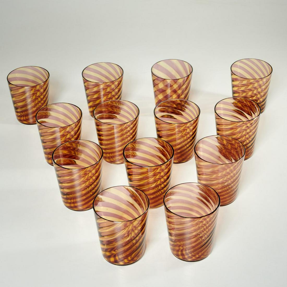Set (13) Venini style swirled glass tumblers: Set (13) Venini style swirled glass tumblers, 20th c., alternating swirled bands of amethyst and lemon yellow, unmarked, 3.75"h x 3"dia. Provenance: Property removed from 760 Park Ave, New York