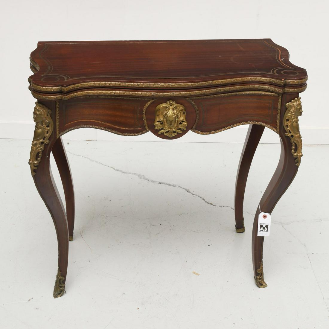 Napoleon III style brass inlaid games table: Napoleon III style brass inlaid games table, 19th/20th c., serpentine front demilune games table, inlaid brass stringing, brass mask head relief mounts, opens to games surface, 31.25"h x 34.5"w x 17.5