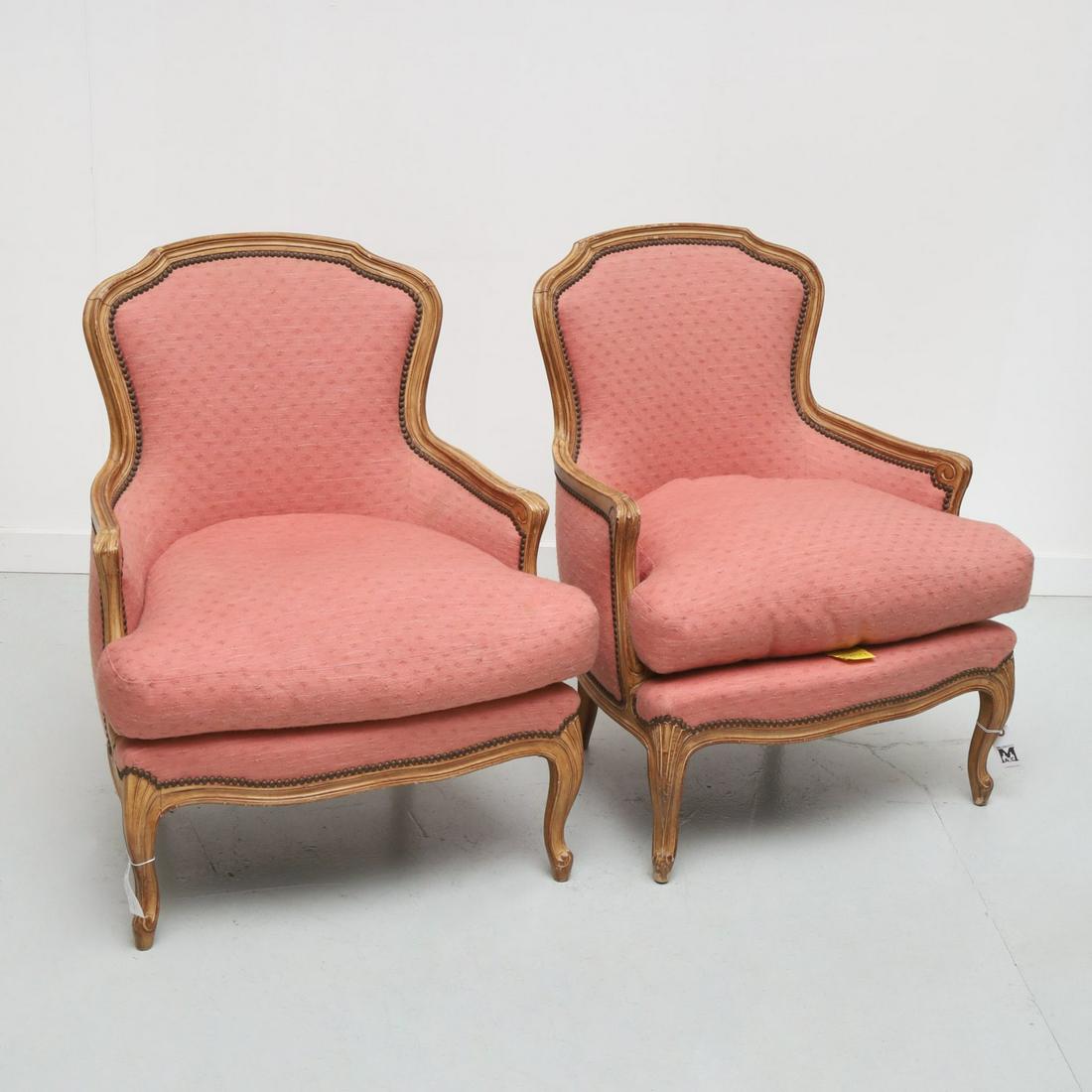 Pair Thomas De Angelis upholstered bergeres: Pair Thomas De Angelis upholstered bergeres, 20th c., New York, Louis XV style in textured pink fabric with nailhead trim, yellow maker's tags, 34.5"h x 26.5"w x 23"d