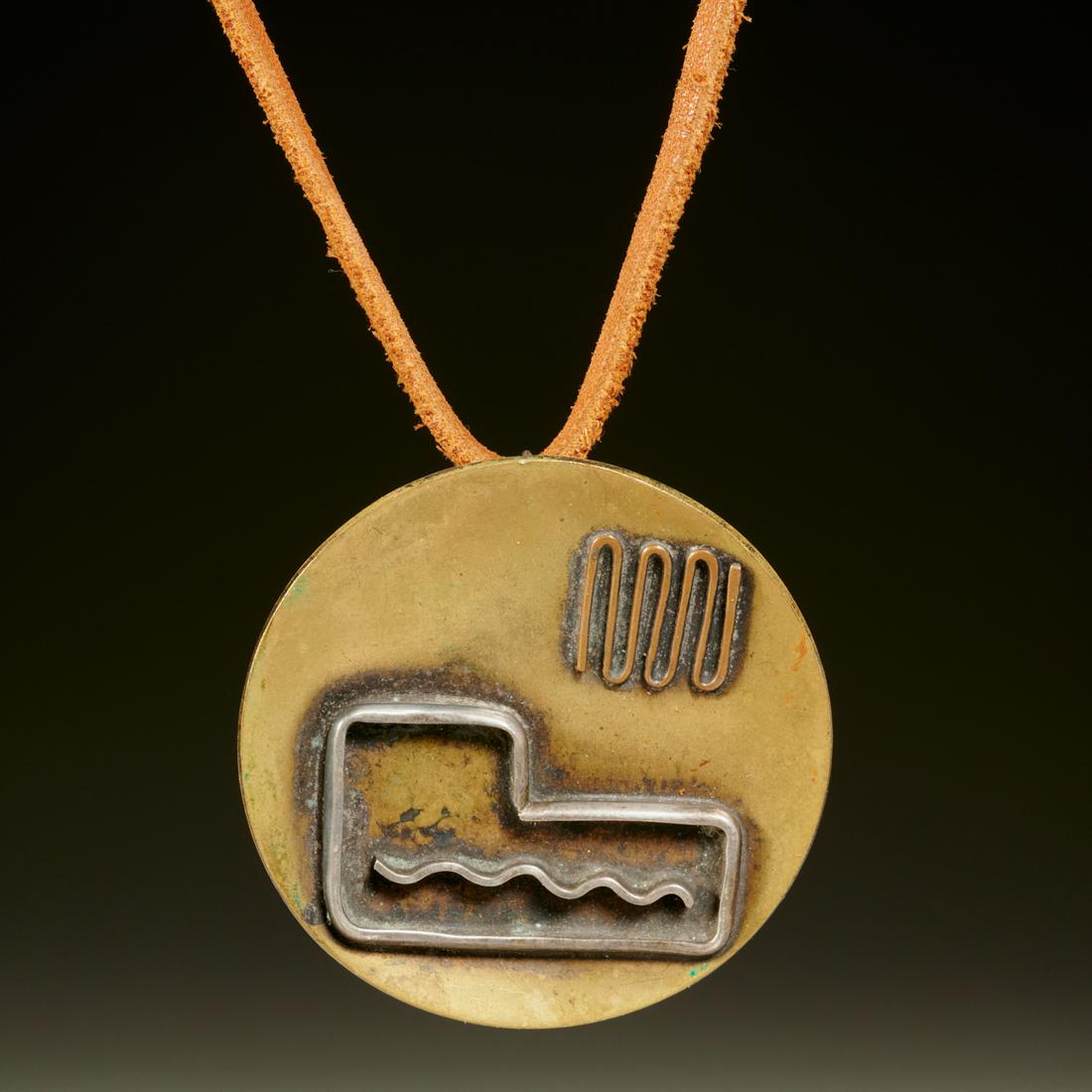 Ed Wiener, modernist pendant: Ed Wiener, modernist pendant, Ed Wiener (American, 1918-1991), hand wrought mixed metal disc pendant with applied design elements, strung on a brown leather strap, stamped signature verso, 2.5"dia. (p
