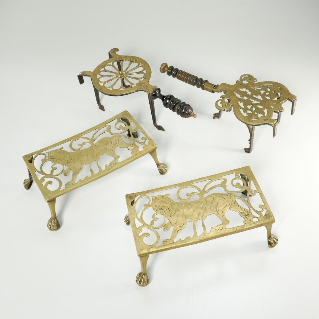 Group (4) antique brass trivets: Group (4) antique brass trivets, 19th c., England, includes two rectangular examples with tigers and ball and claw feet, 4"h x 10.25"w x 5.5"d, and two brass and cast iron with wooden handles and stam