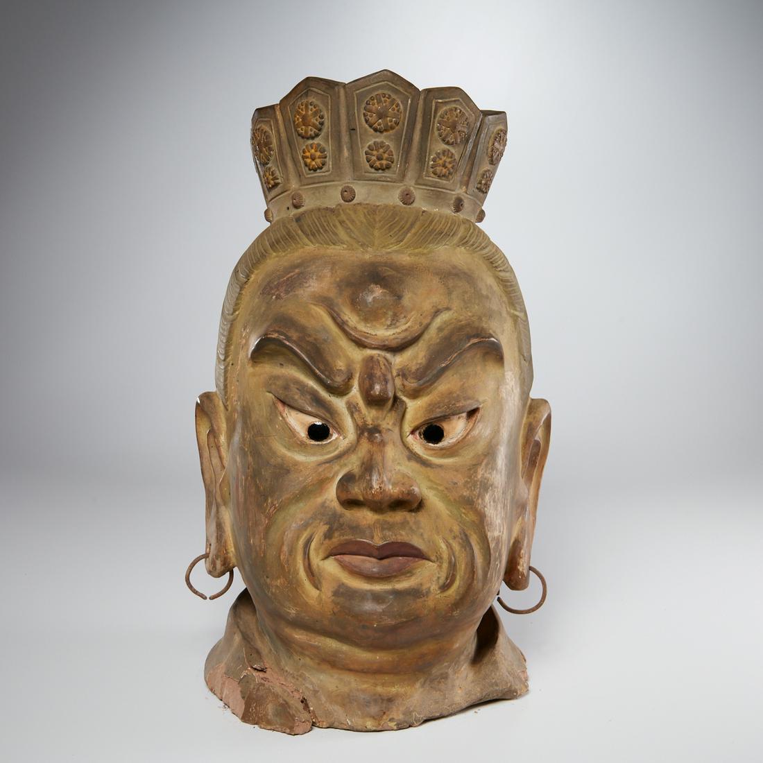 Large earthenware Guardian head fragment: Large earthenware Guardian head fragment, 19th c., likely Japanese, crowned head, face fixed in anger, with inset glass eyes, adorned with metal earrings, approx. 18.5"h x 9"w x 8.5"d Provenance: The