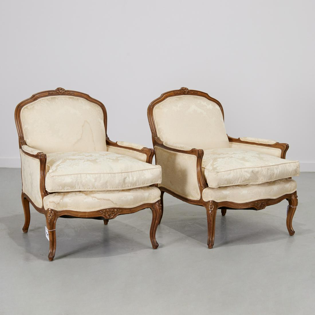 Pair Lous XV style bergeres: Pair Lous XV style bergeres, 20th c., carved mahogany, with floral crest and knees, cream damask upholstery, unmarked, approx. 36"h x 29"w, 24" (seat depth), 36"d (depth from crest to front) Provenanc