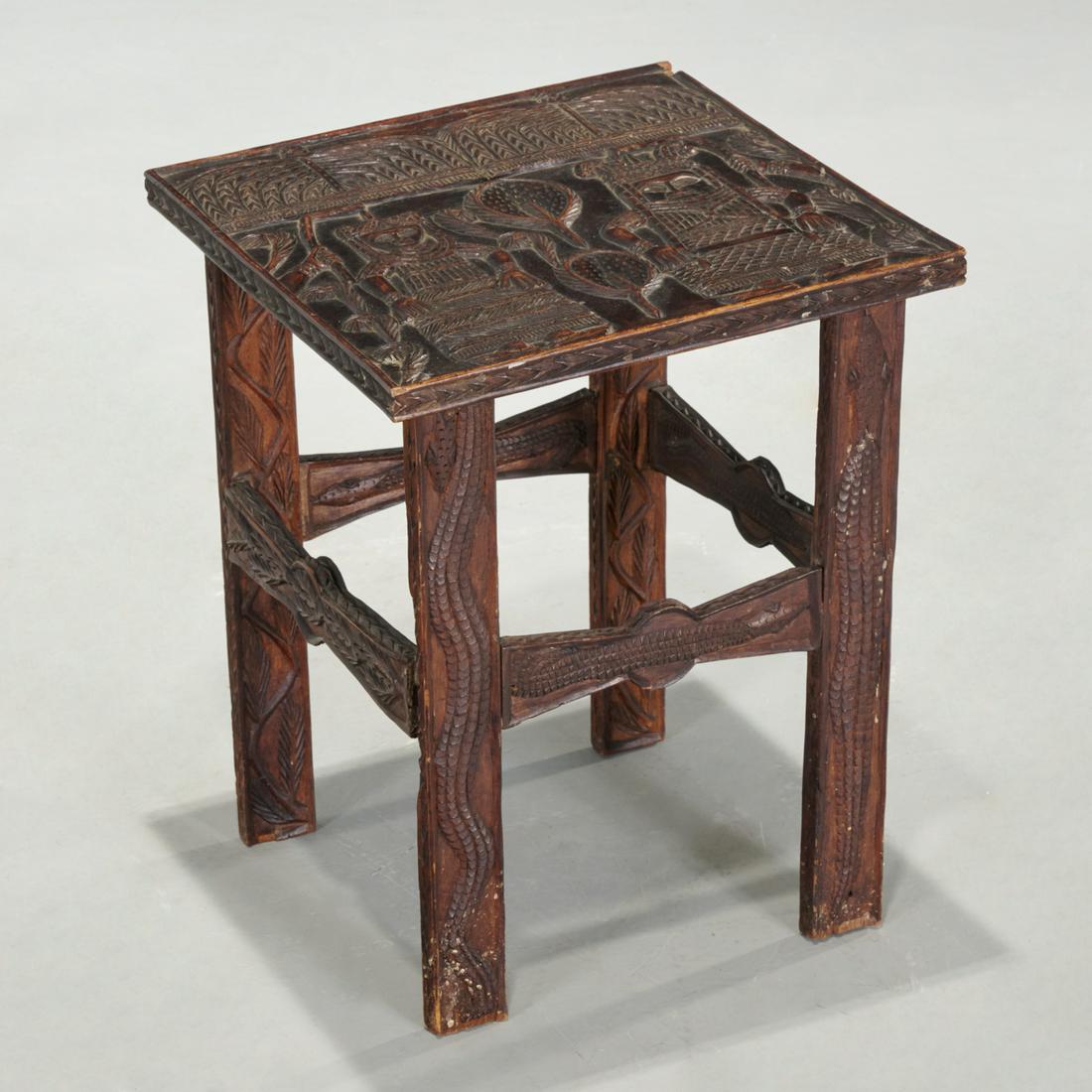 Benin Peoples, carved wood table: Benin Peoples, carved wood table, 20th c., Nigeria, dark stained hardwood, relief carved with a royal couple seated under a thatched structure, fanned by attendants out of frame, the legs and stretche