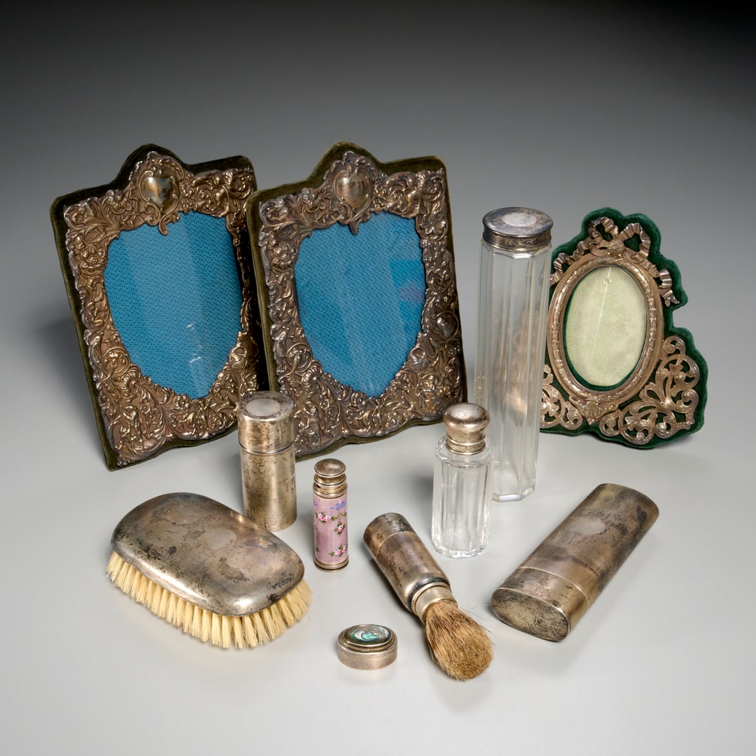 Group Sterling silver vanity items: Group Sterling silver vanity items, 19th/20th c., (11) pieces, incl. (3) velvet backed repousse picture frames, a brush, (2) sterling lidded glass perfume bottles, an oval case, Mexican pill box with