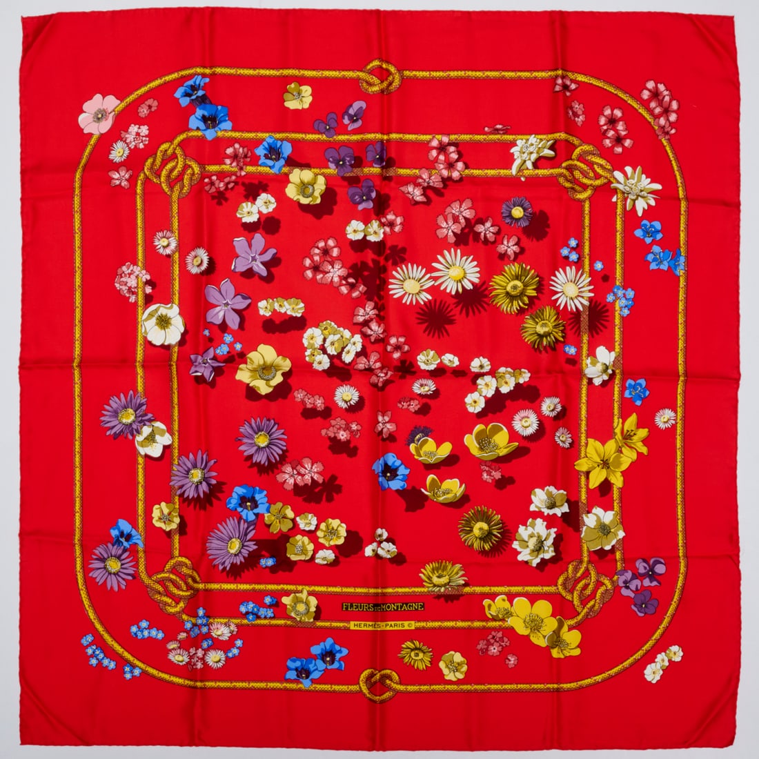 Hermes "Fleurs de Montagne" 90 cm silk scarf: Hermes "Fleurs de Montagne" 90 cm silk scarf, 21st c., Made in France, red with multicolor floral motif, first designed by Cathy Latham in 1982, signed within print, with fabric label, 35" squ Provena