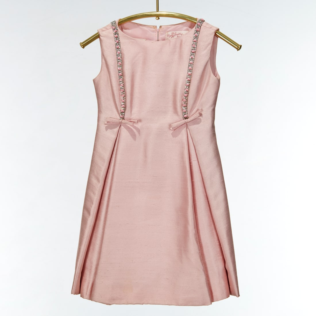 Gino Charles pink silk cocktail dress: Gino Charles pink silk cocktail dress, c. 1960s, for Miss Bergdorf, pale pink shantung with pleated front and sequin bow trim, sleeveless with zipper back, size 4, approx. 32"b, 32"l Provenance: The E