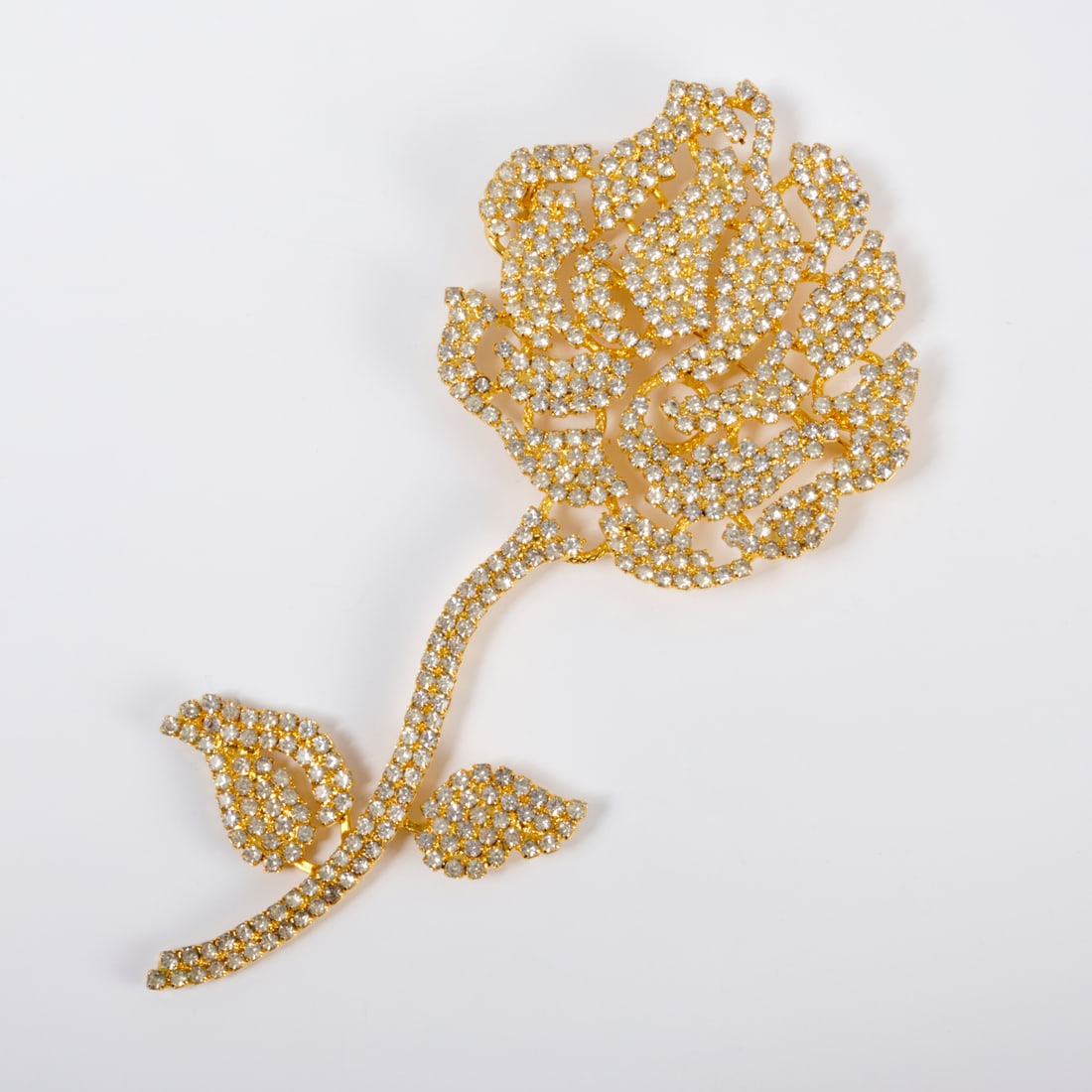 Rare Pauline Trigere rose rhinestone brooch: Rare Pauline Trigere rose rhinestone brooch, c. 1940s, in gold tone metal, art deco style, stamped on verso, approx. 6"h, 2.5"w Provenance: A Private Collection: 1 Sutton Place South, NYC