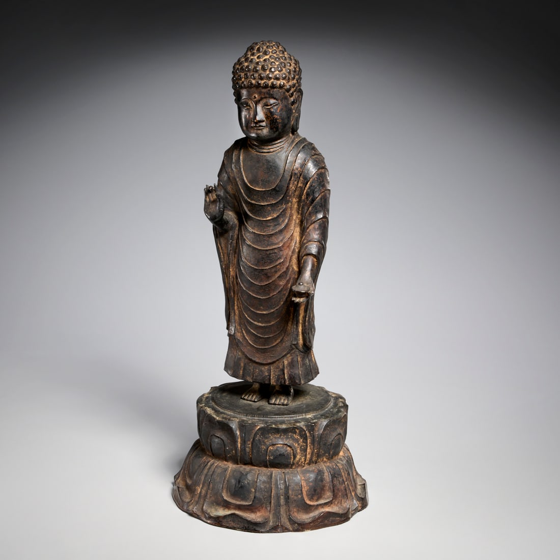 Korean parcel gilt bronze standing Buddha: Korean parcel gilt bronze standing Buddha, Unified Silla style (8th c., CE), Korea, dressed in pleated robe, with tight curly hair, hands in a gesture of protection and compassion, standing on double 