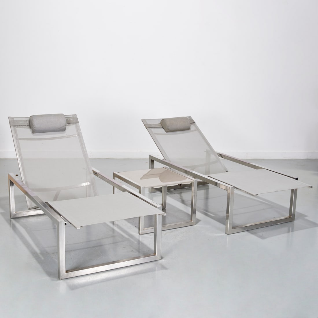 Royal Botania, pair "Ninix" outdoor chaises: Royal Botania, pair "Ninix" outdoor chaises, 20th c., USA, chrome metal square tubing, nylon mesh, with adjustable back angle, 14"h x 77"l x 27"w (chaises), with a complimenting glass top side table,