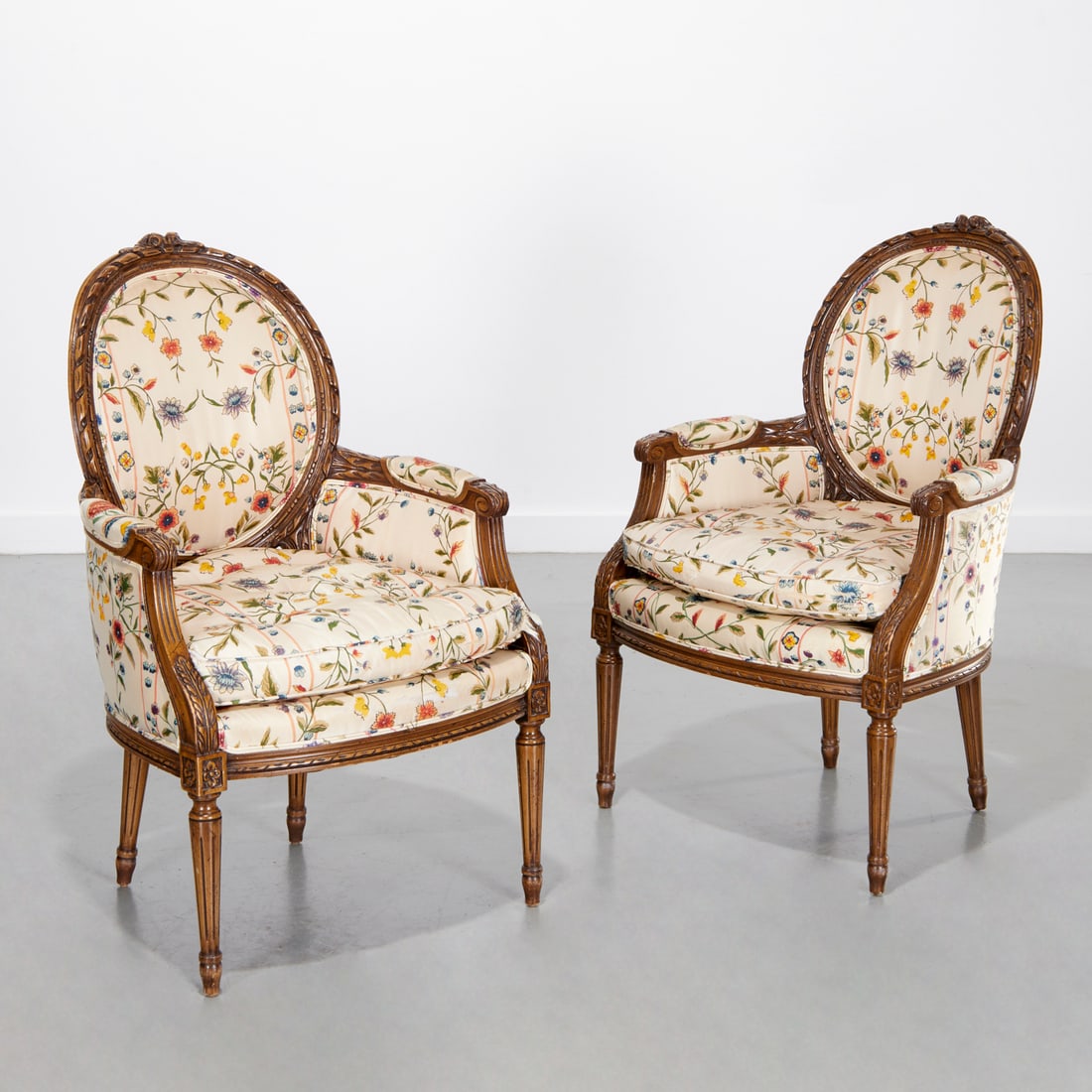Pair Louis XVI style upholstered bergeres: Pair Louis XVI style upholstered bergeres, 20th c., colorful floral design upholstery, unmarked, 38.5"h x 24"w x 21"d, 19"h (to seat)