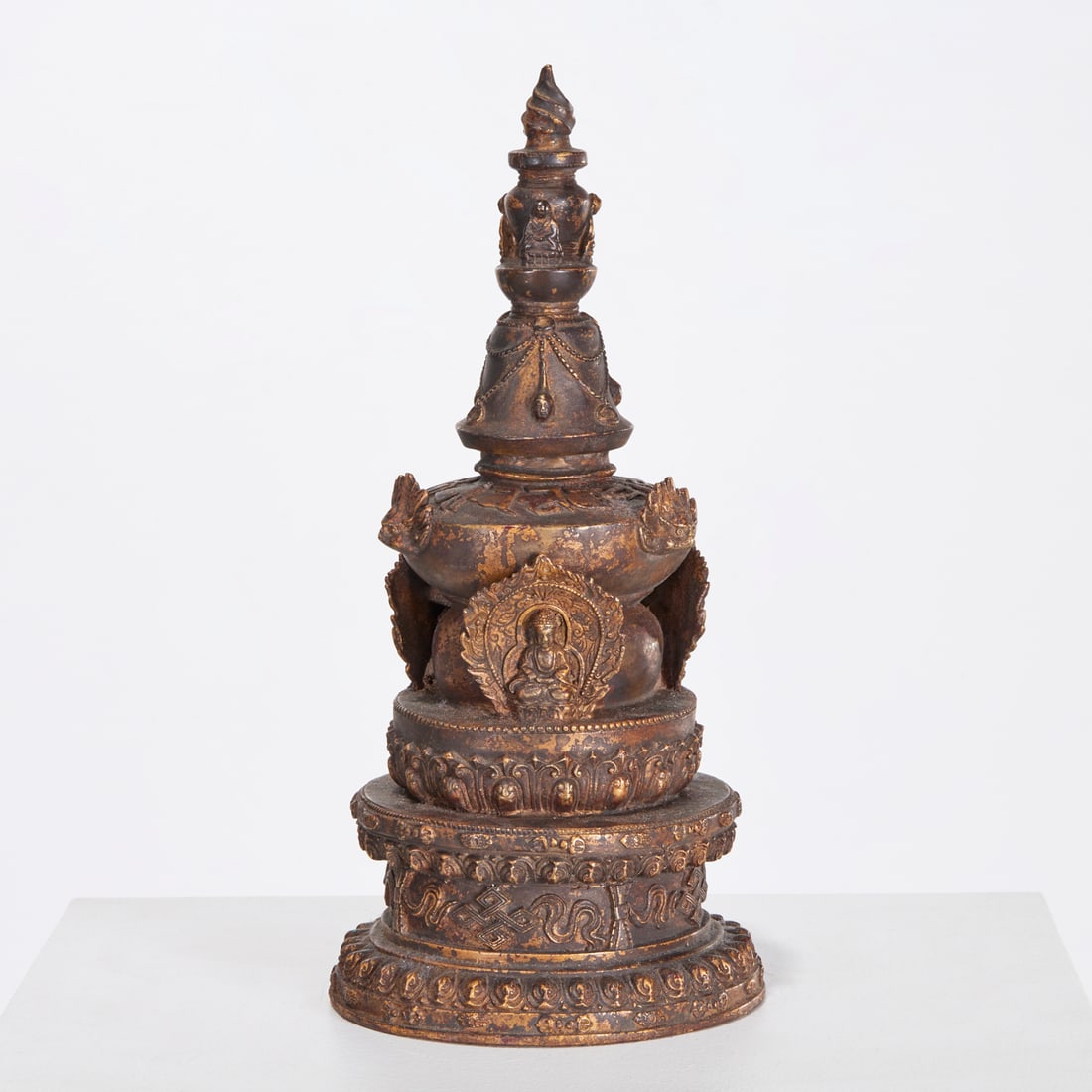 Large antique Tibetan bronze stupa: Large antique Tibetan bronze stupa, 19th/20th c., brown patina with trace gilding, cast as a tiered monument with torch finial, decorated with draped beads, Dorje masks and seated Buddhas, 17"h x 7"di