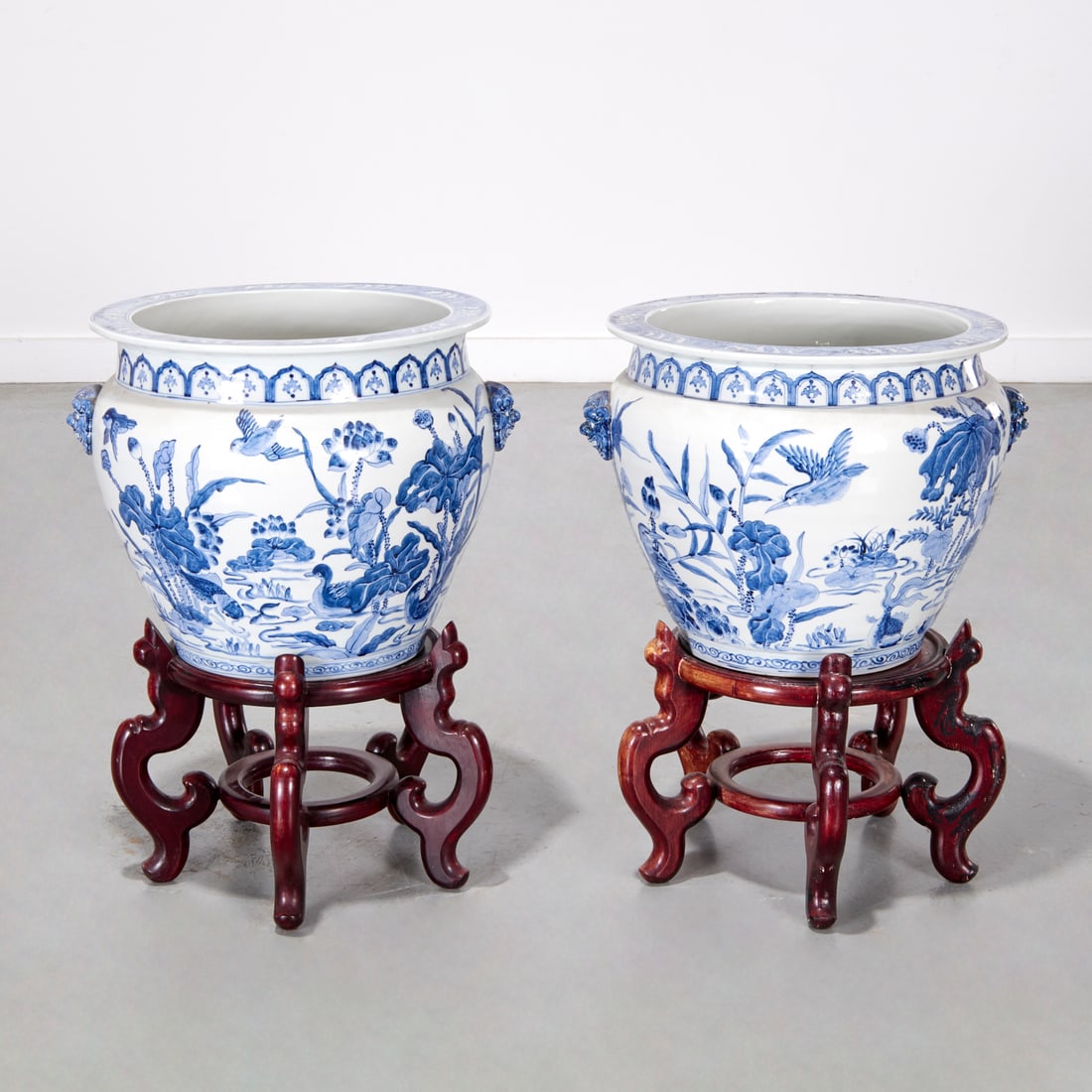 Pair Chinese blue and white porcelain jardinieres: Pair Chinese blue and white porcelain jardinieres, 20th c., decorated with birds and flowers, mounted with foo beast handles, on hardwood stands, unmarked, 14.5"h x 18.5"w x 16"d (jardinieres only), 2