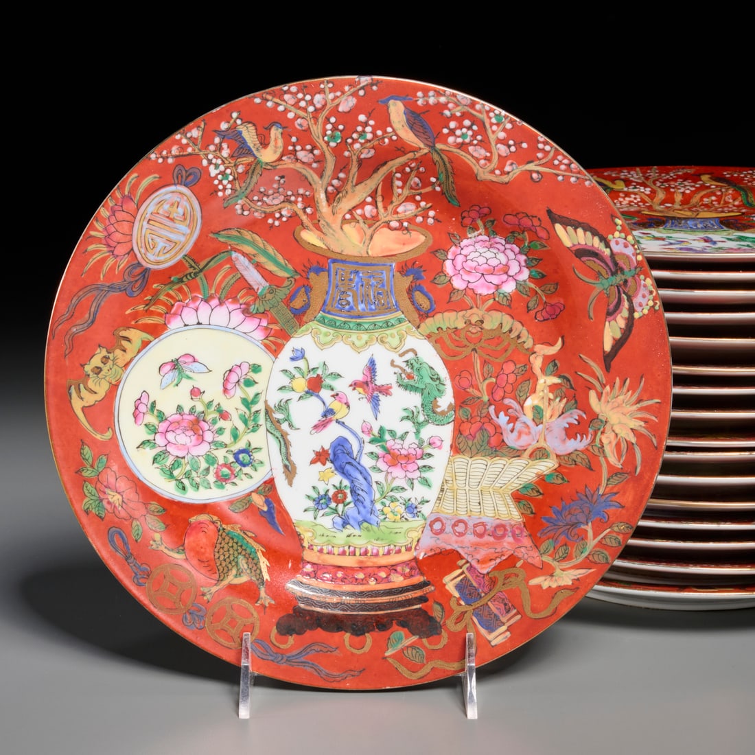Set (17) Chinese Export porcelain dinner plates: Set (17) Chinese Export porcelain dinner plates, 20th c., iron red ground decorated with vase, basket, birds, butterfly, bat, and flowers, unmarked, 10.5"dia Provenance: The Iris Apfel Collection
