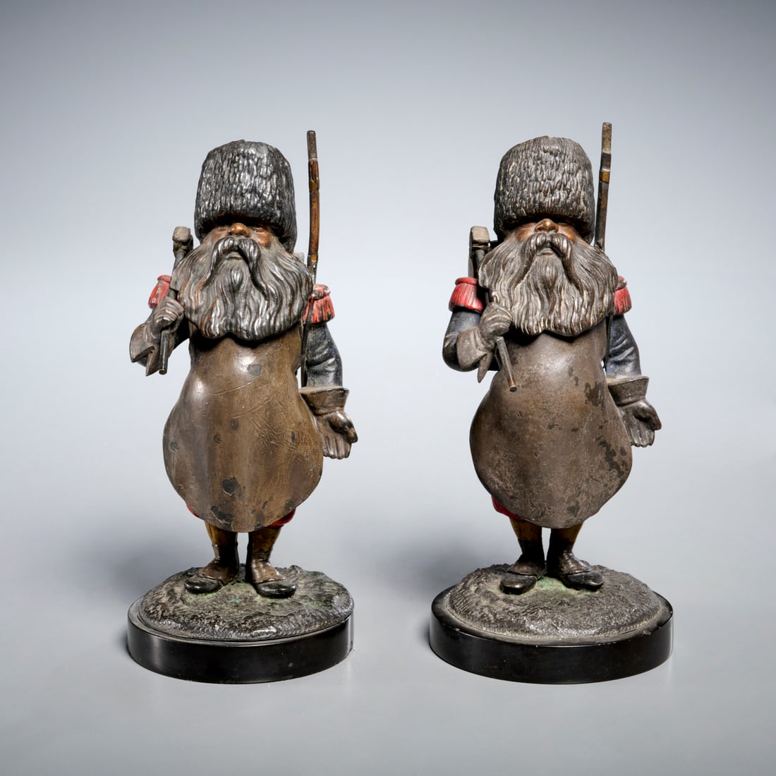 Pair antique bronze Russian soldier inkwells: Pair antique bronze Russian soldier inkwells, 19th/20th c., cold-painted bronze or copper alloy, bearded soldiers with ax, backpack and rifle, hinged head, one with porcelain insert, one with brass, u
