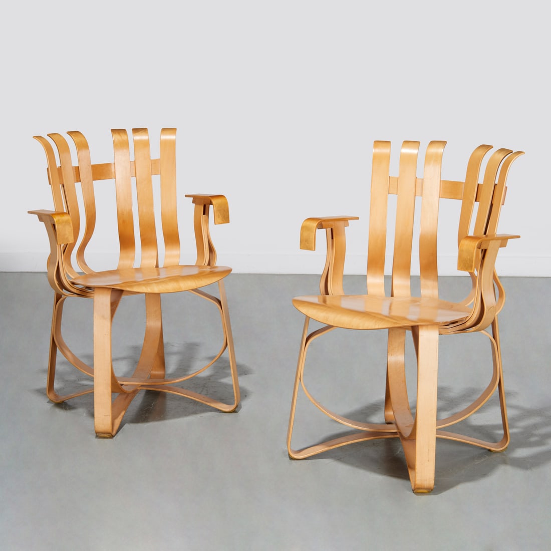 Pair Frank Gehry for Knoll "hat trick" armchairs: Pair Frank Gehry for Knoll "hat trick" armchairs, 20th c., USA, bentwood chairs, curvilinear slatted back with sloped armrests, raised on entwined stretcher legs, branded underside, each 34"h x 23'w x