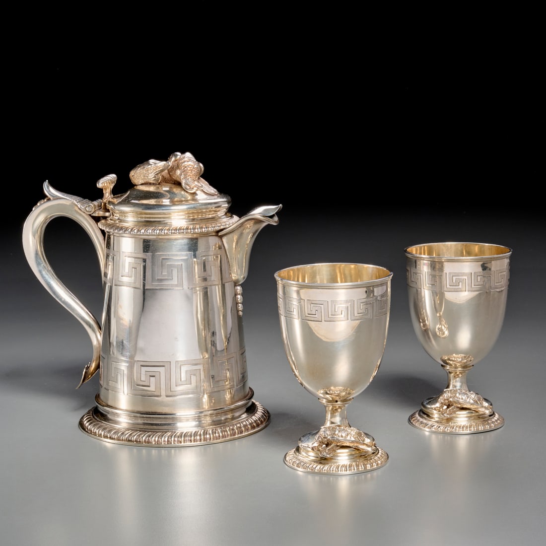 Tiffany silver pitcher and goblets, c. 1870: Tiffany silver pitcher and goblets, c. 1870, England, mark of Tiffany & Co., tankard with gadrooned base rim, body engraved with two bands of Greek key, hinged cover with finial modeled as a pair of s