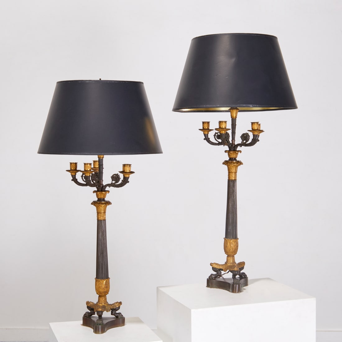 Pair Charles X bronze candelabra lamps: Pair Charles X bronze candelabra lamps, 19th c., converted to electricity, two-light, five candlestick arms of foliate and rosette scrolls on fluted column stems, terminating in acanthus leaf tripod b
