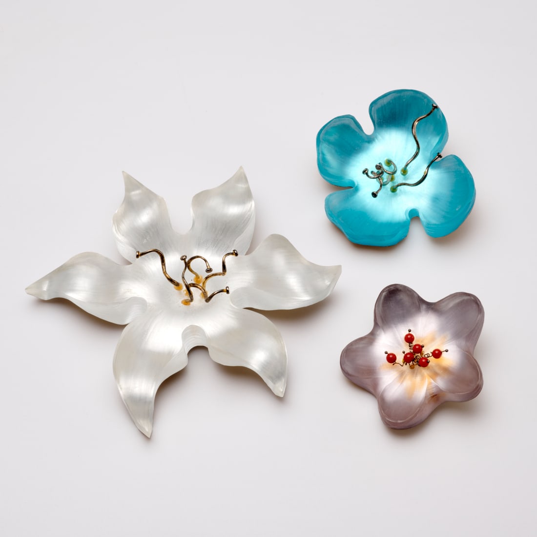 Group of Alexis Bittar Lucite brooches: Group of Alexis Bittar Lucite brooches, 21st c., all in flower form with lacquer backs, with Alex Bittar gold nameplate on verso, largest white, 4" dia., smallest mauve, 1.75" dia Provenance: From the