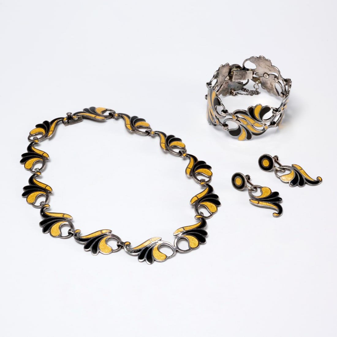 Margot de Taxco Silver & enamel jewelry suite: Margot de Taxco Silver & enamel jewelry suite, Mid 20th c., Made in Mexico, including necklace with yellow speckled and black enamel in spiraling foliate link design, 15"l, bracelet of same design, 1.