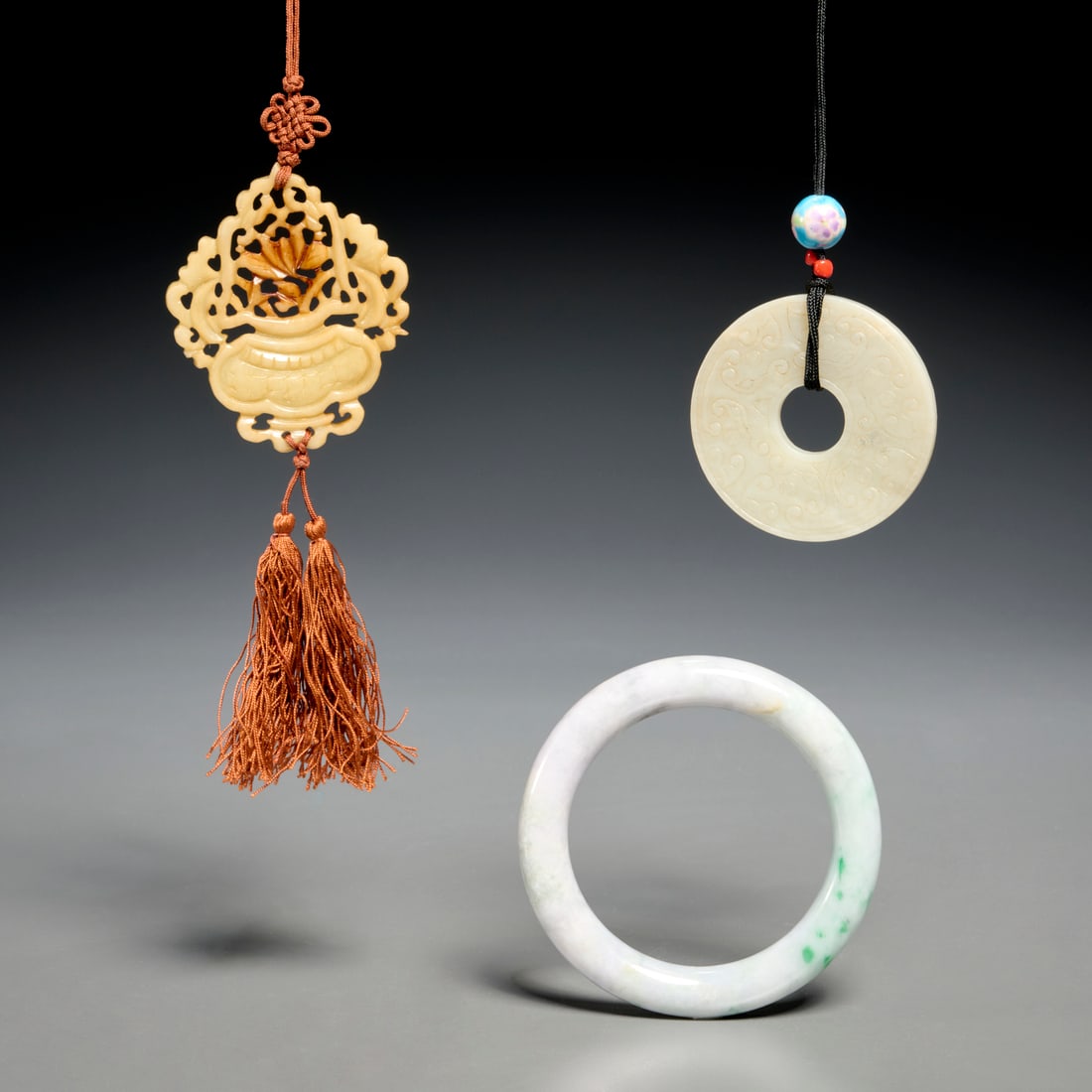 (3) Chinese jade toggles and bangle: (3) Chinese jade toggles and bangle, Late Qing Dynasty (19th/20th c.), or later, incl. (1) jade disc toggle with geometric carvings, (1) pierced jade floral urn toggle, (1) jade bangle, each