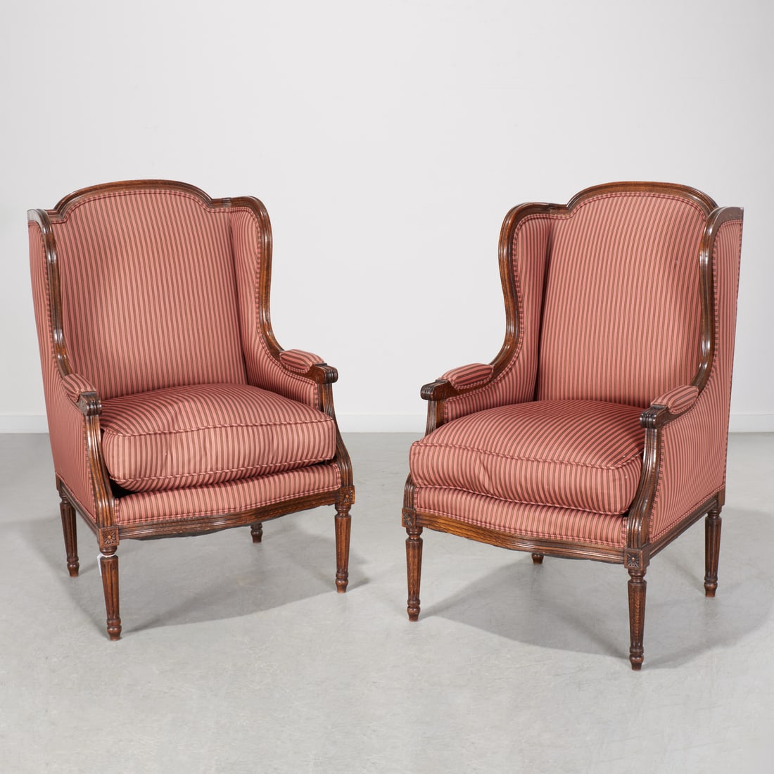 Pair Louis XVI style winged beechwood bergeres: Pair Louis XVI style winged beechwood bergeres, 20th c., cranberry striped silk upholstery, unmarked, 41"h x 25.5"w x 24.5"d Provenance: A Private Collection: 860 Fifth Avenue, NYC
