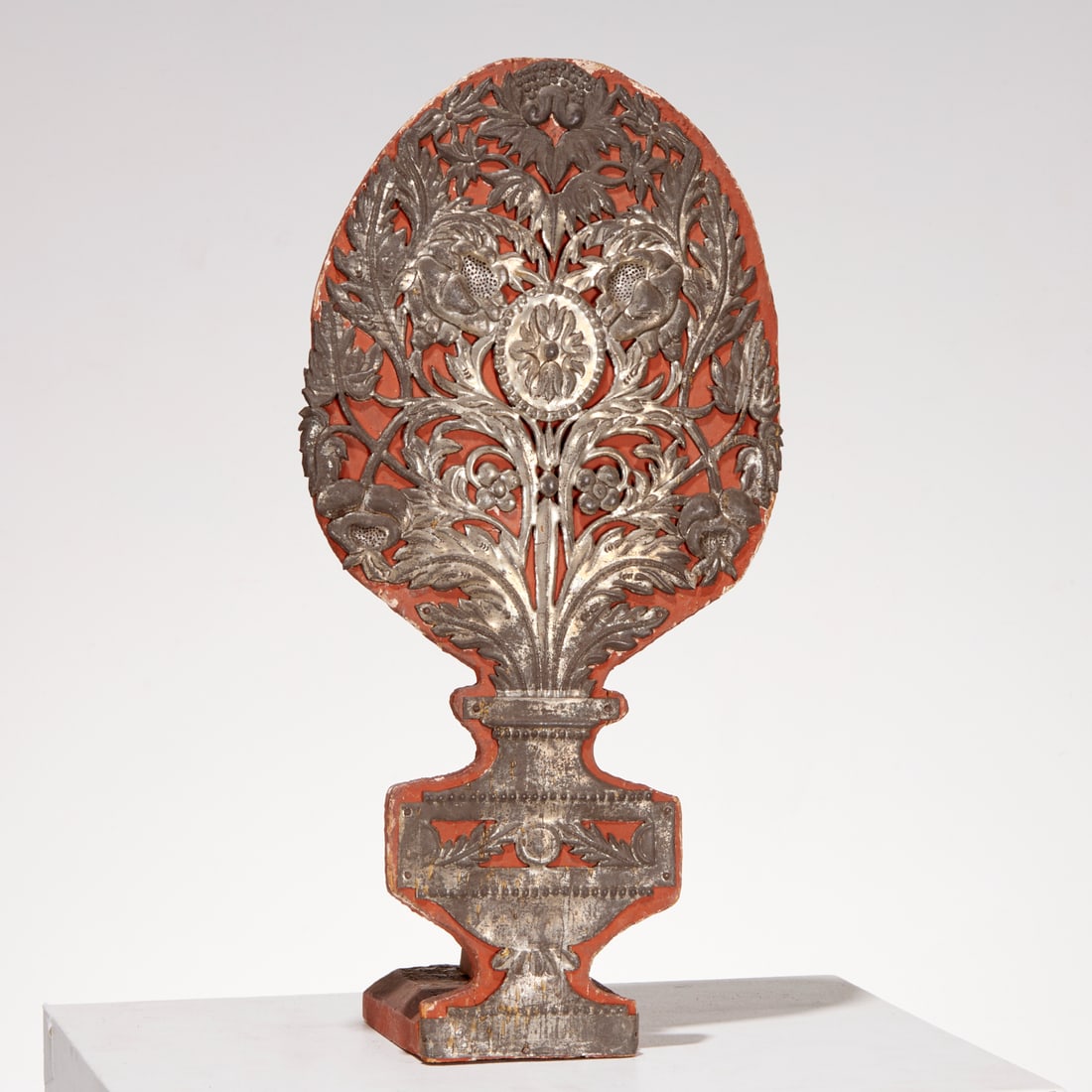 Continental tin portapalma altar ornament: Continental tin portapalma altar ornament, 19th c., openwork silvertone sheet metal flower urn, mounted on painted wood backdrop stand, 22"h x 11.25'w x 6.5"d Provenance: The Iris Apfel Collection