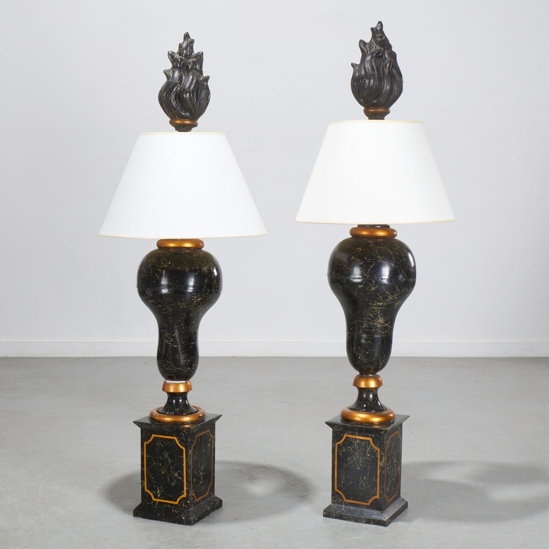 Pair over-sized Neoclassical style tole lamps: Pair over-sized Neoclassical style tole lamps, Mid 20th c., parcel gilt faux marbre decoration, of urn-form on stepped base with large flame finials, each 63.5"h x 11"dia (lamp only) Provenance: A