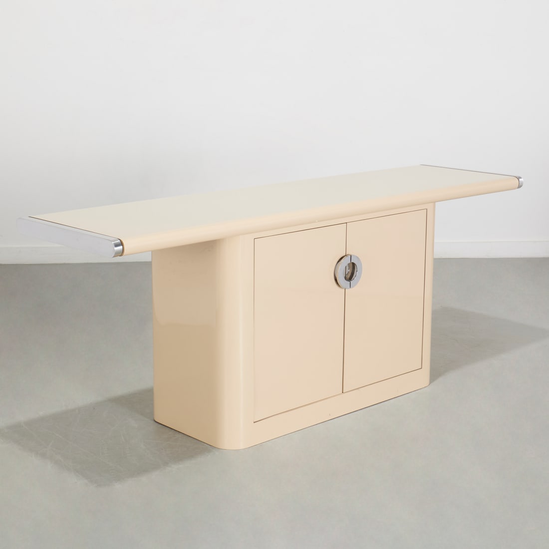 Pierre Cardin style lacquer console: Pierre Cardin style lacquer console, c. 1970/80s, cream lacquer with chrome mounts, double door panels, unmarked, 29"h x 74.5"w x 20"d Provenance: Property from a Prominent NYC Family Foundation
