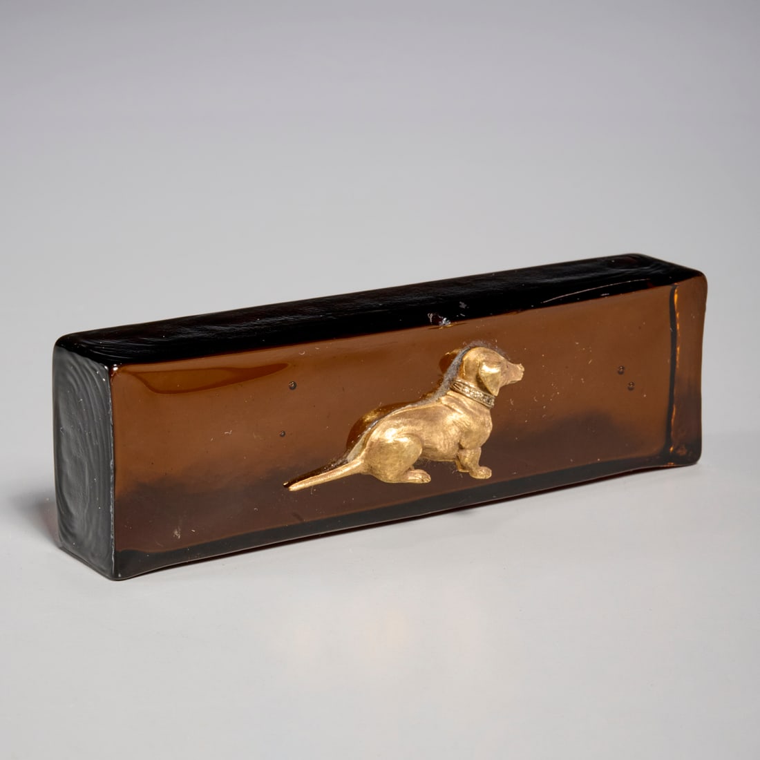 18k gold and diamond Dachshund paperweight: 18k gold and diamond Dachshund paperweight, 20th c., gold with diamond collar, mounted on amber glass block, no mark observed, strongly tests for 18k, 1.25"h x 4.25"l x 1.25"w Provenance: The Collecti