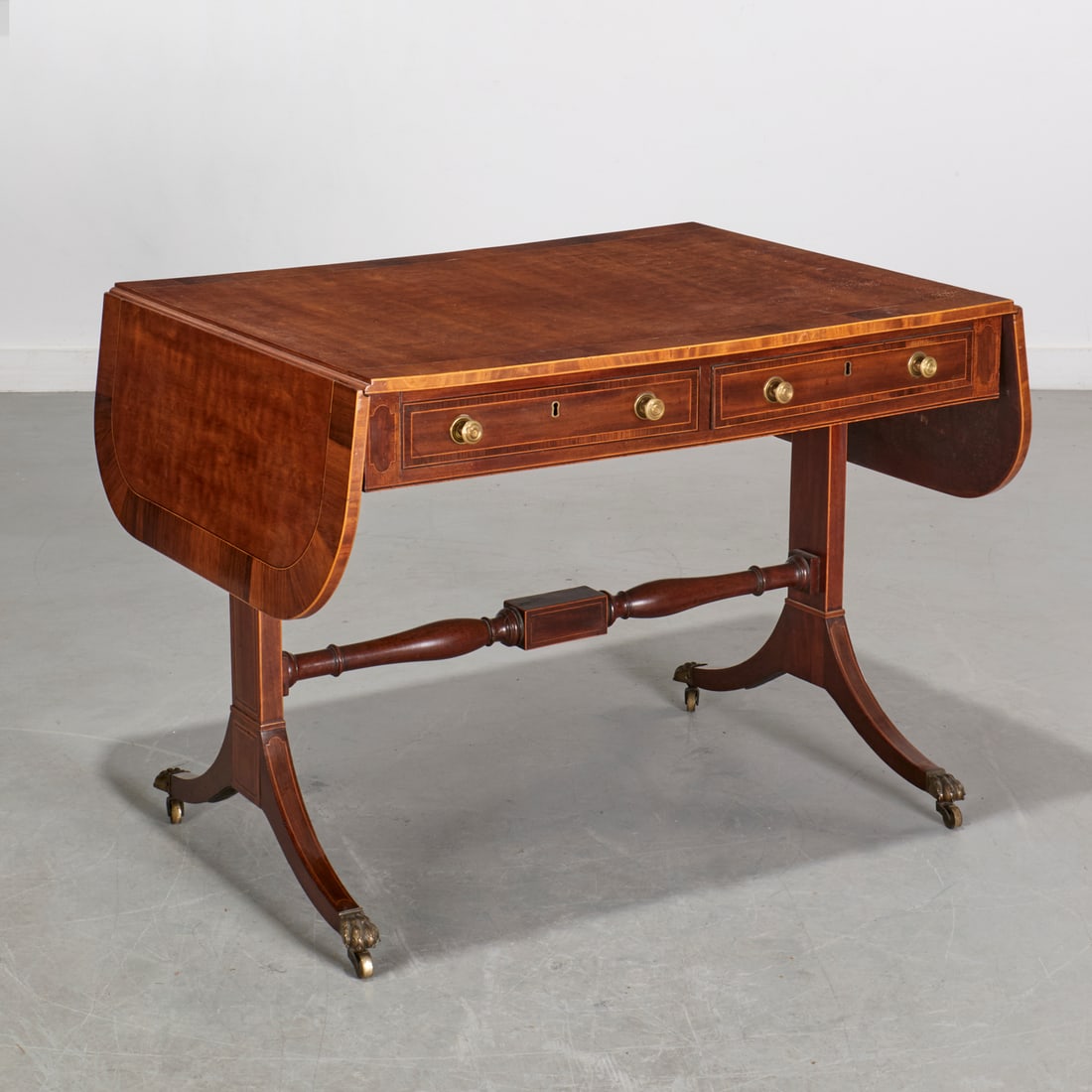 Regency banded burlwood sofa table: Regency banded burlwood sofa table, 19th c., England, rectangular top with drop leaf sides, two frieze drawers, on trestle supports with brass capped paw feet and casters, 28"h x 36.5"w x 28"d, 59.5"w