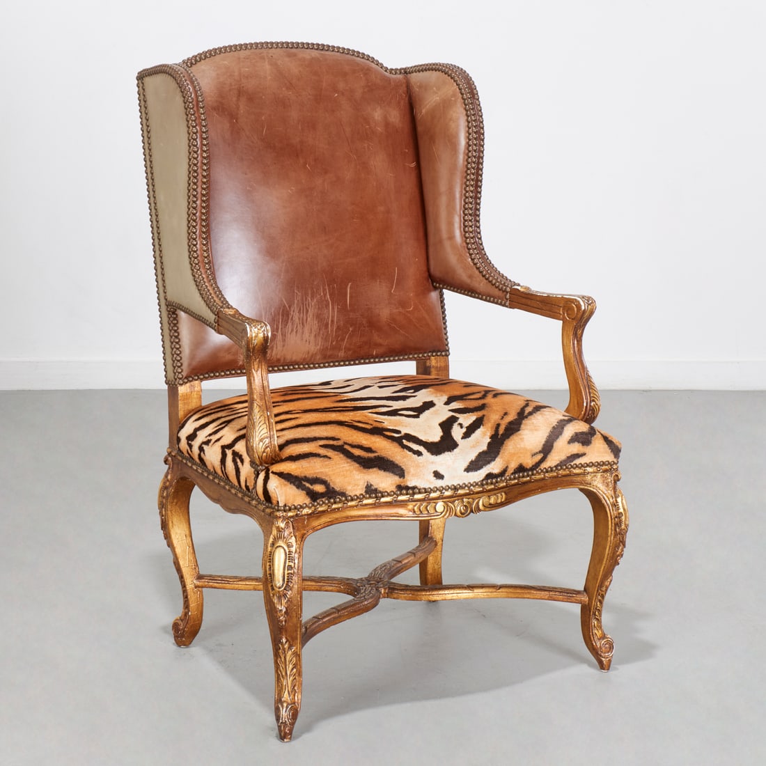 Ralph Lauren "Spencer" wing back chair: Ralph Lauren "Spencer" wing back chair, 20th c., carved giltwood frame, brown leather upholstered back with nailhead trim, silk animal print upholstery to seat, on cabriole legs with X-form