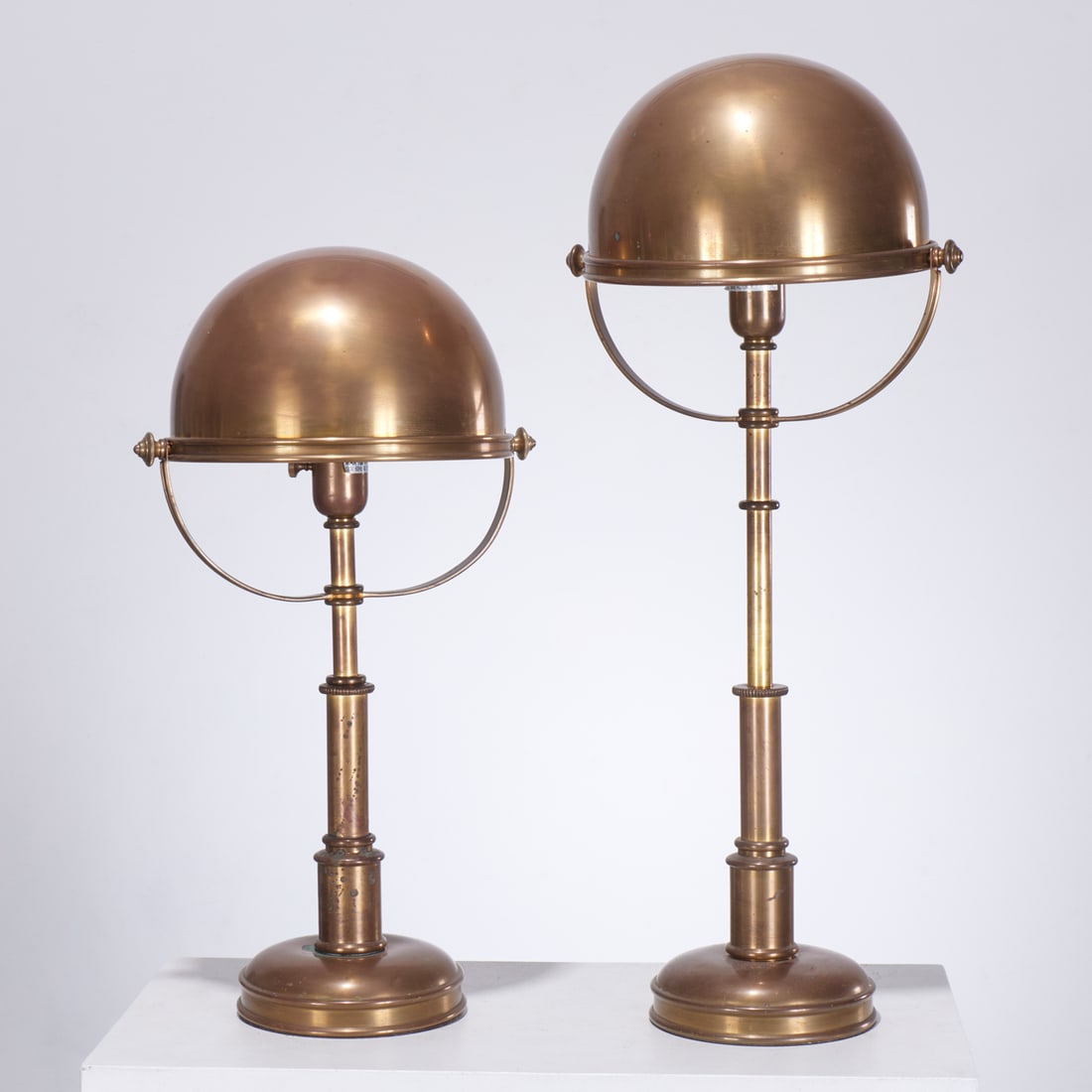 Ralph Lauren, pair brass telescope lamps: Ralph Lauren, pair brass telescope lamps, 20th c., adjustable height with swivel dome shade, marked edge of base, tagged to wires, 23.5"h x 12.5"w x 10.25"d (smaller), 29"h x 12.5"w x 10.25"d