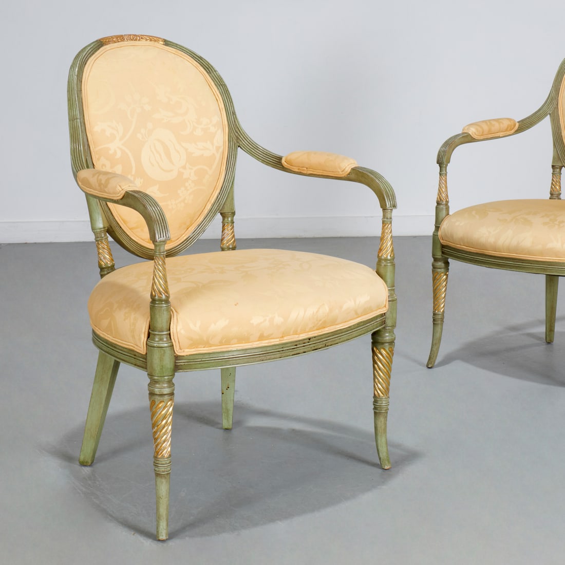Italian Neoclassical style painted, gilt armchairs: Italian Neoclassical style painted, gilt armchairs, Mid 20th c., pistachio green finish, each concave oval backrest with gilt foliate crest, on round tapering spiral-fluted legs, golden yellow upholst