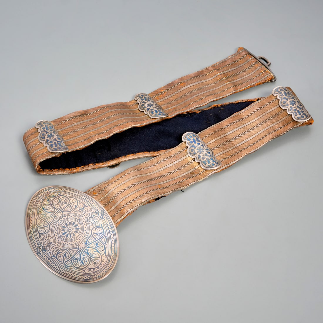 Russian silver niello belt, for Tiffany & Co.: Russian silver niello belt, for Tiffany & Co., 19th/20th c., hand-sewn belt of metallic fabric, buckle and ornaments with scrolling designs, back of buckle stamped with two Cyrillic letters and "84"