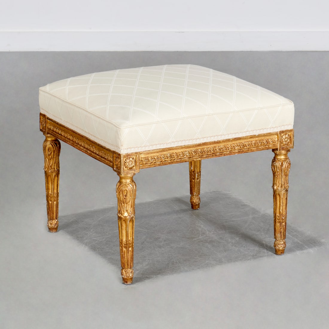 Louis XVI giltwood tabouret: Louis XVI giltwood tabouret, Late 18th c., France, square cream upholstered seat, intricately carved frame with rosette corners, leaf-and-dart border, raised on foliate carved fluted legs, 17"h x 19.5