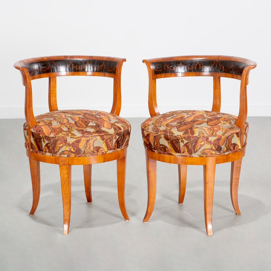 Nice pair Austrian Biedermeier armchairs: Nice pair Austrian Biedermeier armchairs, 19th c., Austria, scrolled tablet crest rail with inlaid ebonized panel, circular seat with embroidered butterfly upholstery, on saber legs, each 29.5"h x 22.