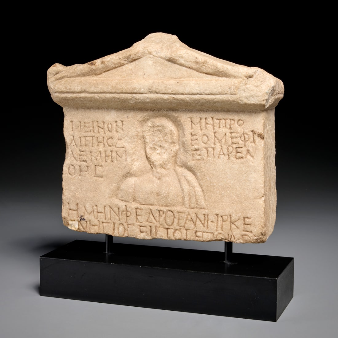 Greek limestone funerary stele: Greek limestone funerary stele, Possibly c. 2nd-3rd c. AD, carved limestone in architectural form with portrait of man to center, inscribed throughout, on custom base, 13"h x 11.5"w 4"d (total), 9.5"h