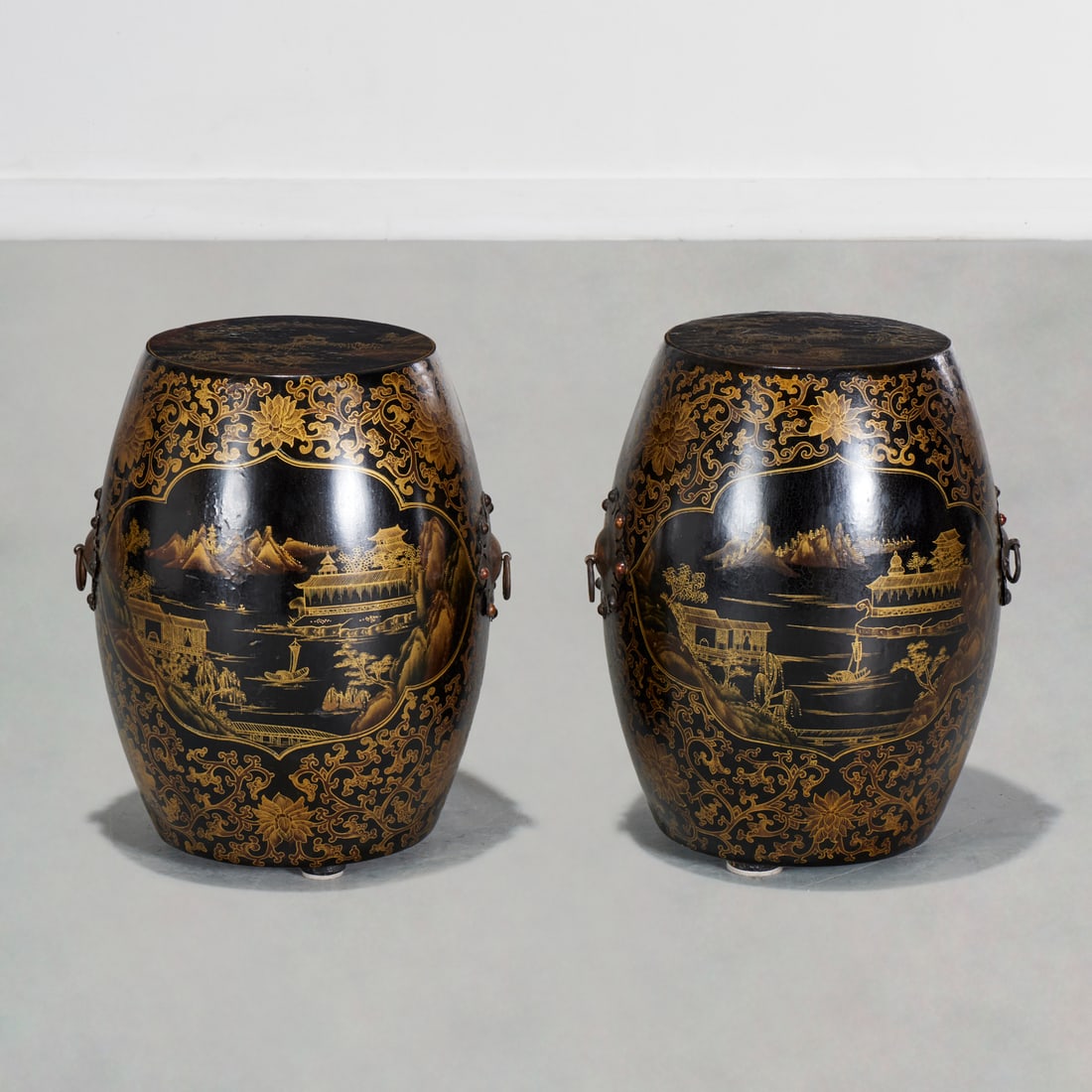 Pair Chinese gilt lacquer barrel garden seats: Pair Chinese gilt lacquer barrel garden seats, 20th c., black and gold landscape scenes, metal ring handles, unmarked, 17"h x 13"w, 9.25"dia (top surface)