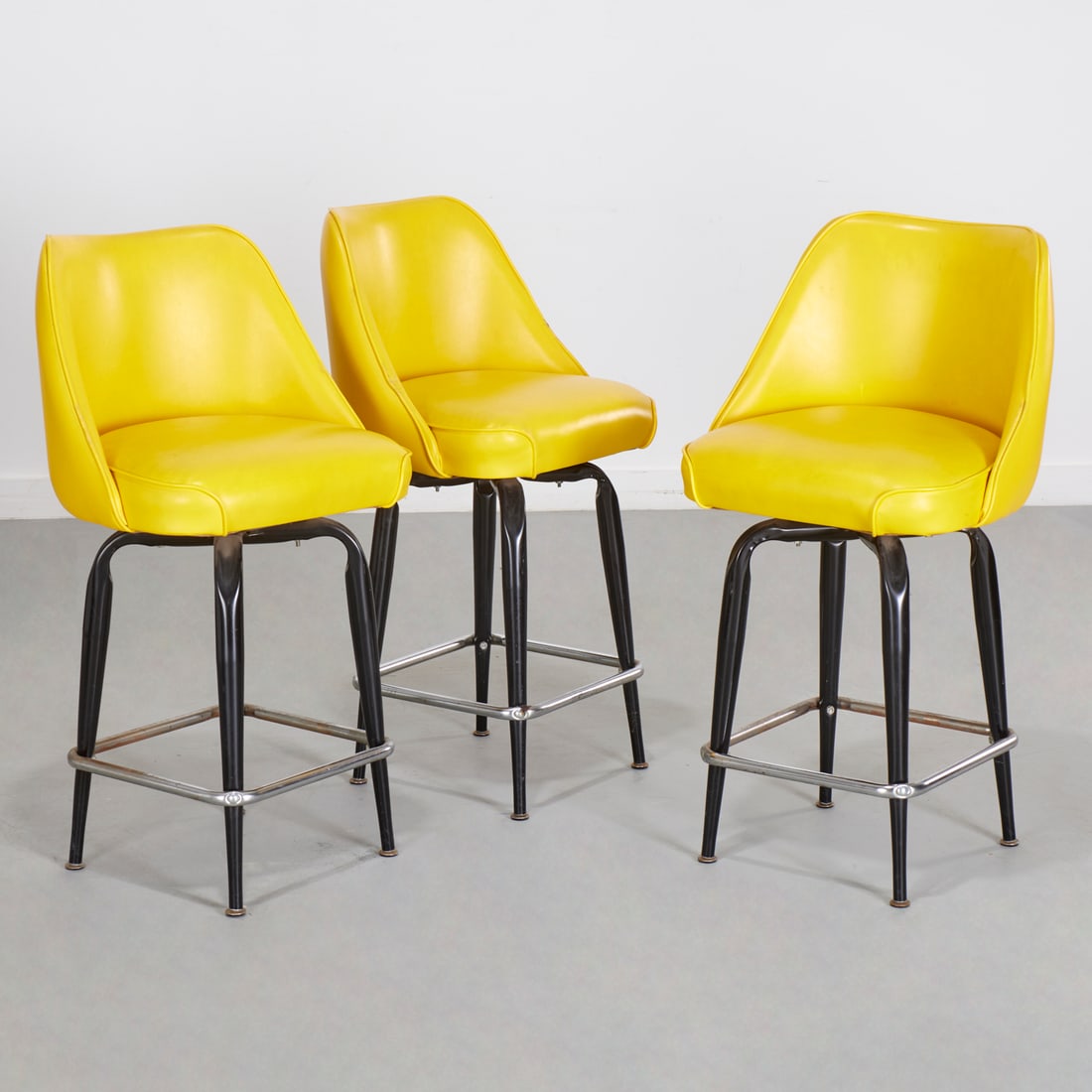 Set (3) MCM yellow counter stools: Set (3) MCM yellow counter stools, Mid 20th c., lemon yellow vinyl upholstery, tapering black patinated metal legs, with chromed metal stretcher, unmarked, 35.5"h x 18.5"w x 16.5"d Provenance: A