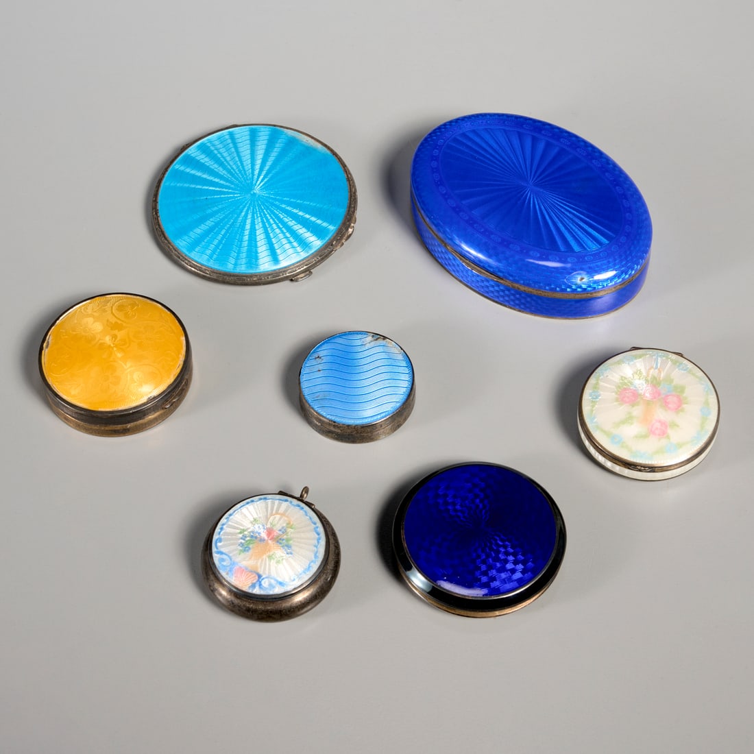 (7) sterling mounted guilloche enamel compacts: (7) sterling mounted guilloche enamel compacts, 19th/20th c., England and Continental, compacts and lidded trinket boxes, with blue, yellow, and floral decorated enamel lids, some with mirrored interi