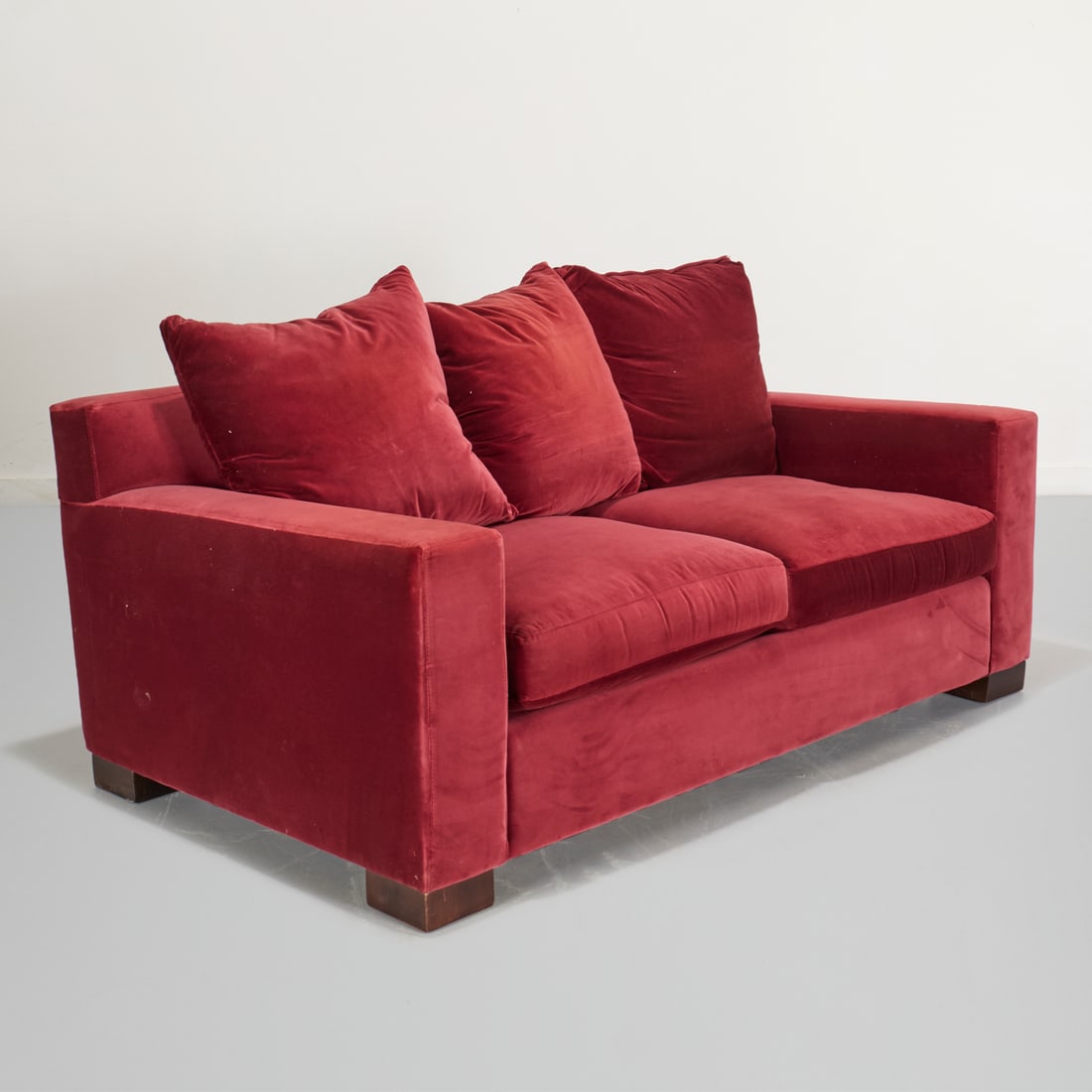 DWR burgundy velvet sofa: DWR burgundy velvet sofa, 21st c., two seat sofa with loose down filled cushions, on block feet, tagged under cushions, 30"h x 71.5"w x 41"d