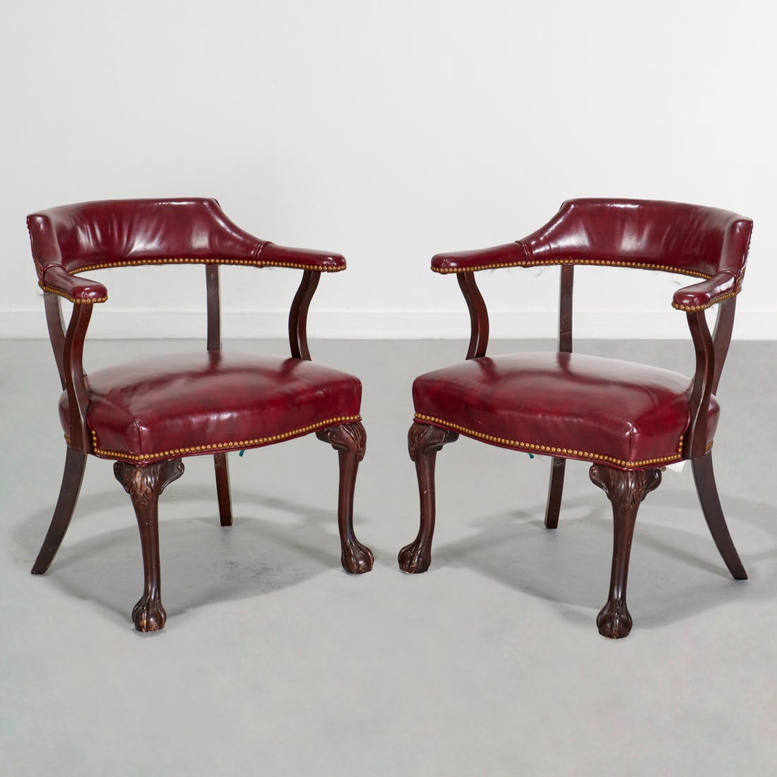 Pair mahogany and leather captain's chairs: Pair mahogany and leather captain's chairs, 20th c., oxblood leather upholstery with nail head trim, claw and ball feet, label of "Janess, North Carolina" to underside of seat, 30"h x 26.5"w x 19"d