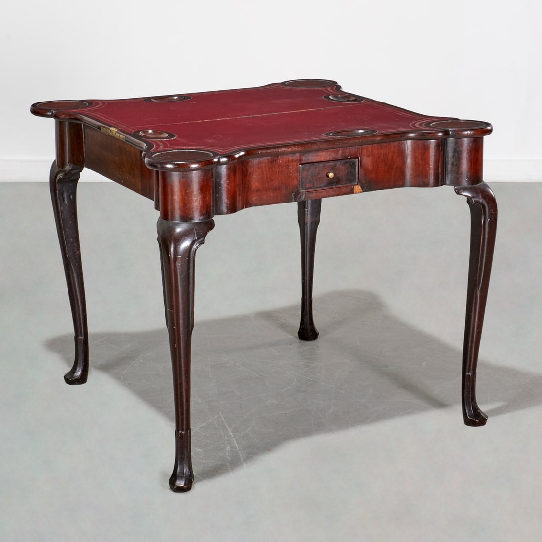Queen Anne style mahogany and leather card table: Queen Anne style mahogany and leather card table, 19th c. and adapted, England, tooled red leather top, on cabriole legs with faceted pad feet, 28.75"h x 34"w x 33.5"d Provenance: The Estate of Camill