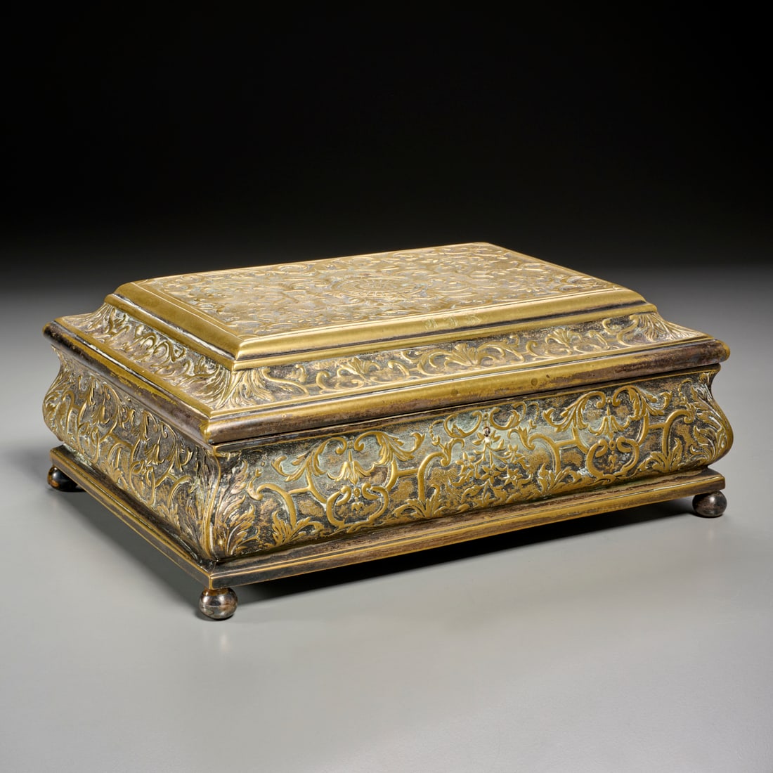 Renaissance Revival silvered brass box: Renaissance Revival silvered brass box, 19th c., rosette medallion to center of hinged lid, scroll and floral decoration throughout, opens to wood lined interior, monogrammed edge, raised on ball feet