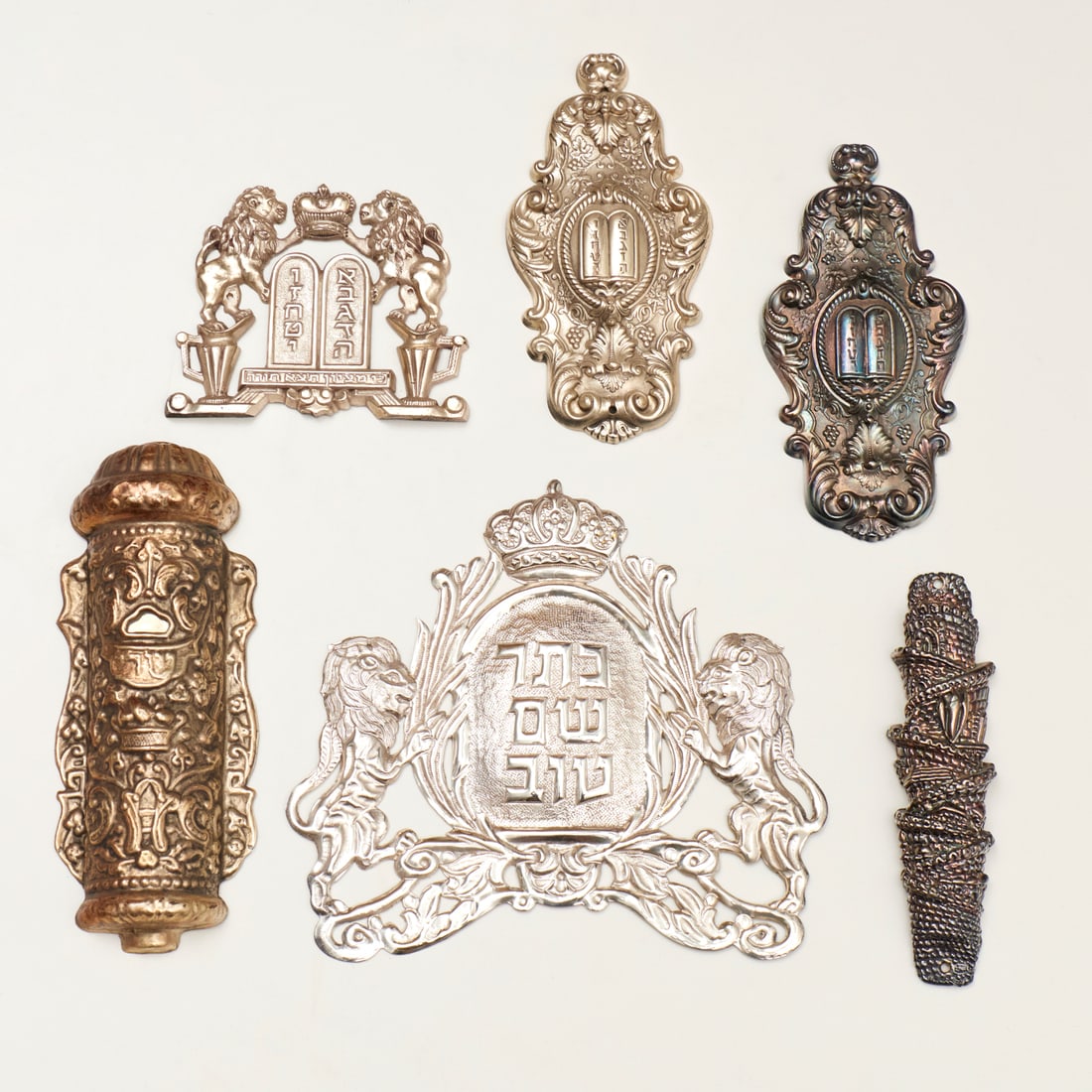 Group (6) torah adornments and mezuzahs: Group (6) torah adornments and mezuzahs, 20th c., incl. a silver mezuzah in the form of a spiral tower, stamped "925", 6.75"l, approx. 1.9ozt; other white metal and silverplate ornaments, 8"h x 9"w